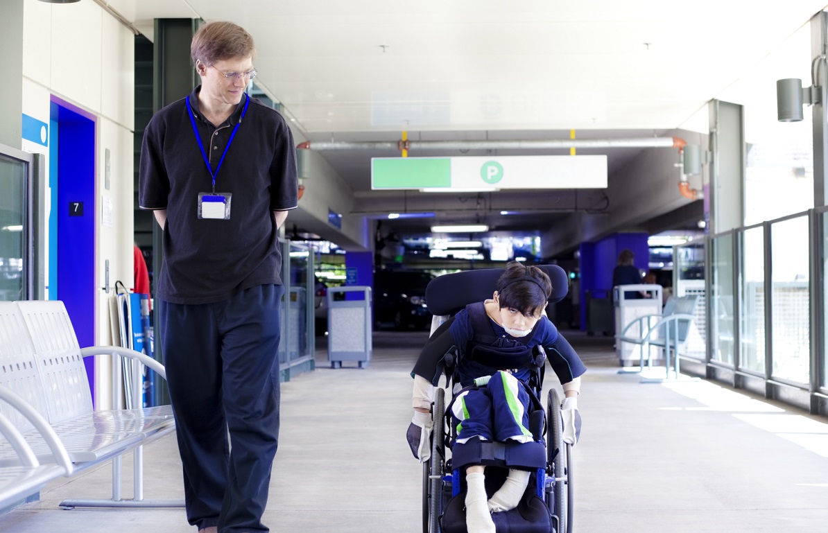 man with child in a wheelchair in a hospital setting man with child in hospital
